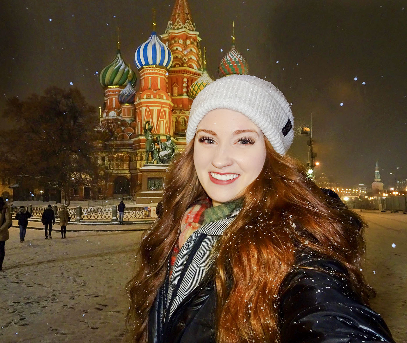 Callie smiling in a snowy city with her hat, hair, and full face visible