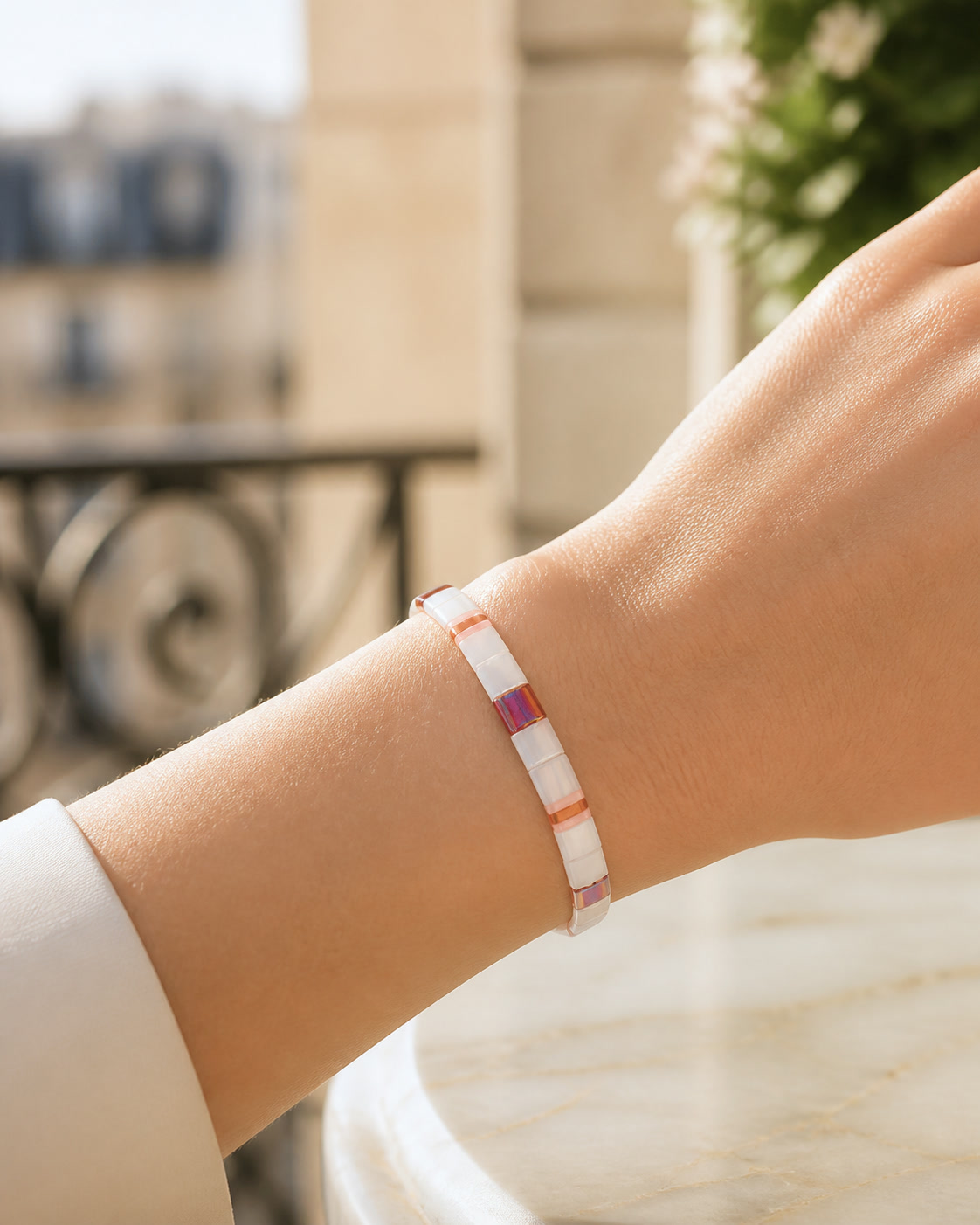 Paris editorial concept of a pearl-white and blush tile bracelet worn snugly on a sunlit wrist