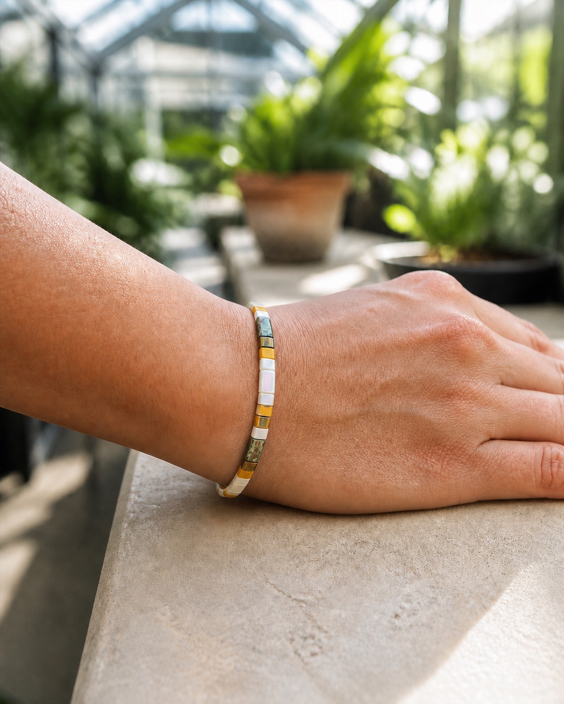 Seville bracelet worn snugly on a wrist in a sunlit greenhouse